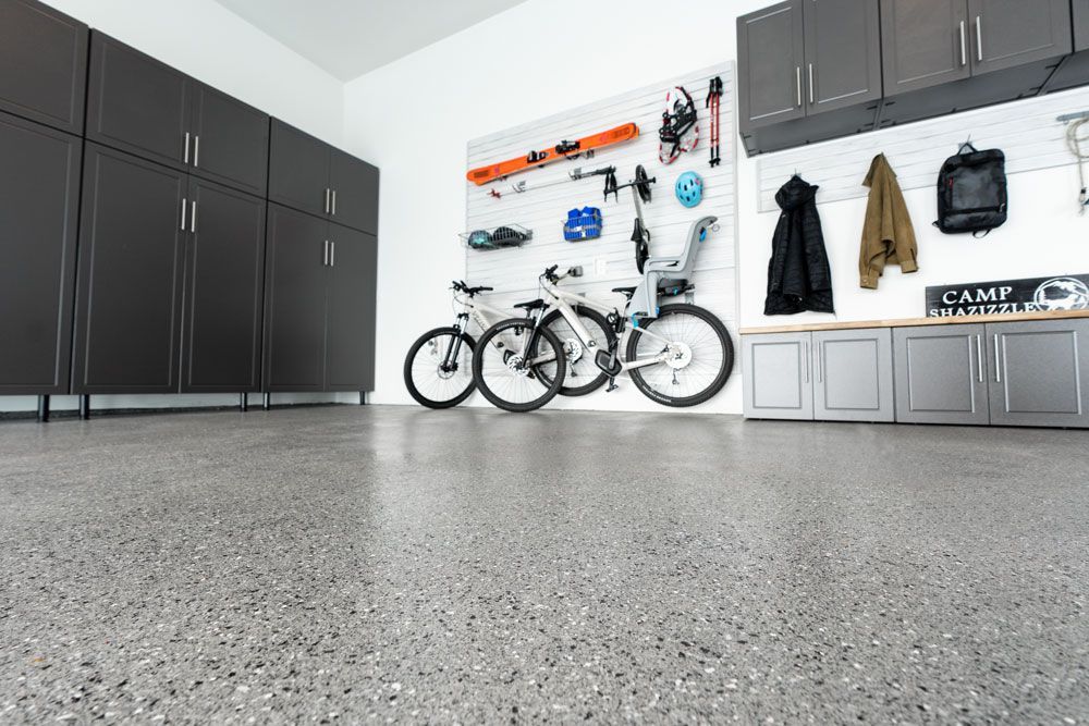 A garage with a lot of cabinets and bikes on the floor.