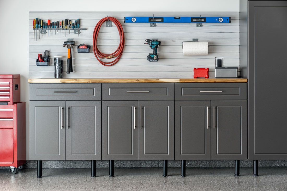 A garage with gray cabinets and a wooden counter top.