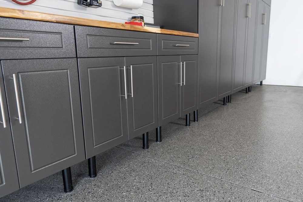 A kitchen with a lot of cabinets and drawers and a concrete floor.