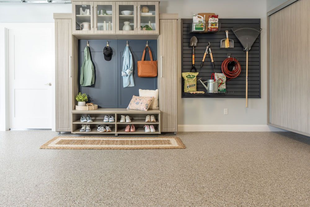 A garage with a bench , cabinets , shelves , and hooks on the wall.