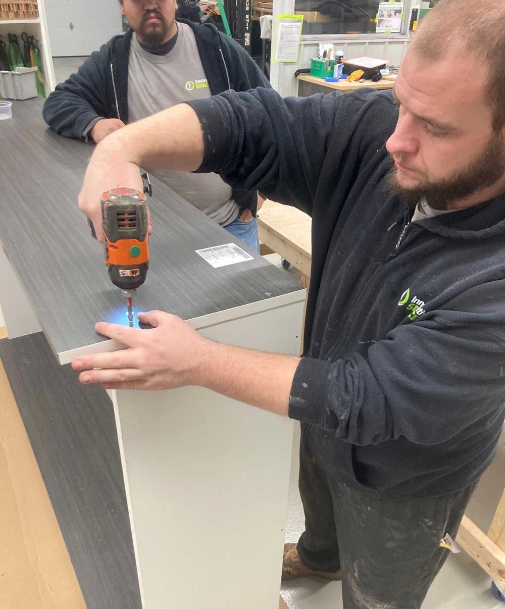 A person is using a drill to drill a hole in a counter top.