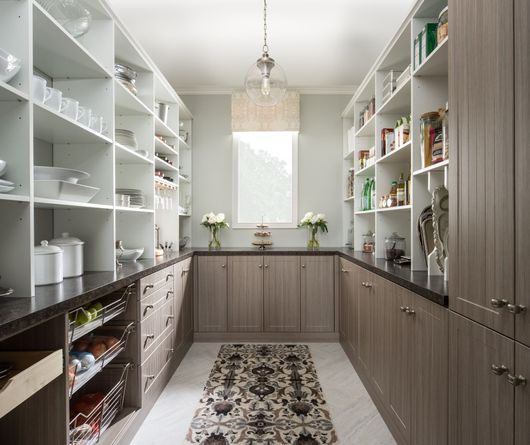 A kitchen pantry with lots of shelves and cabinets and a rug on the floor