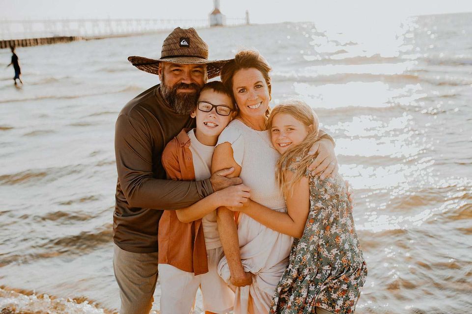 A family is posing for a picture on a wooden bridge.
