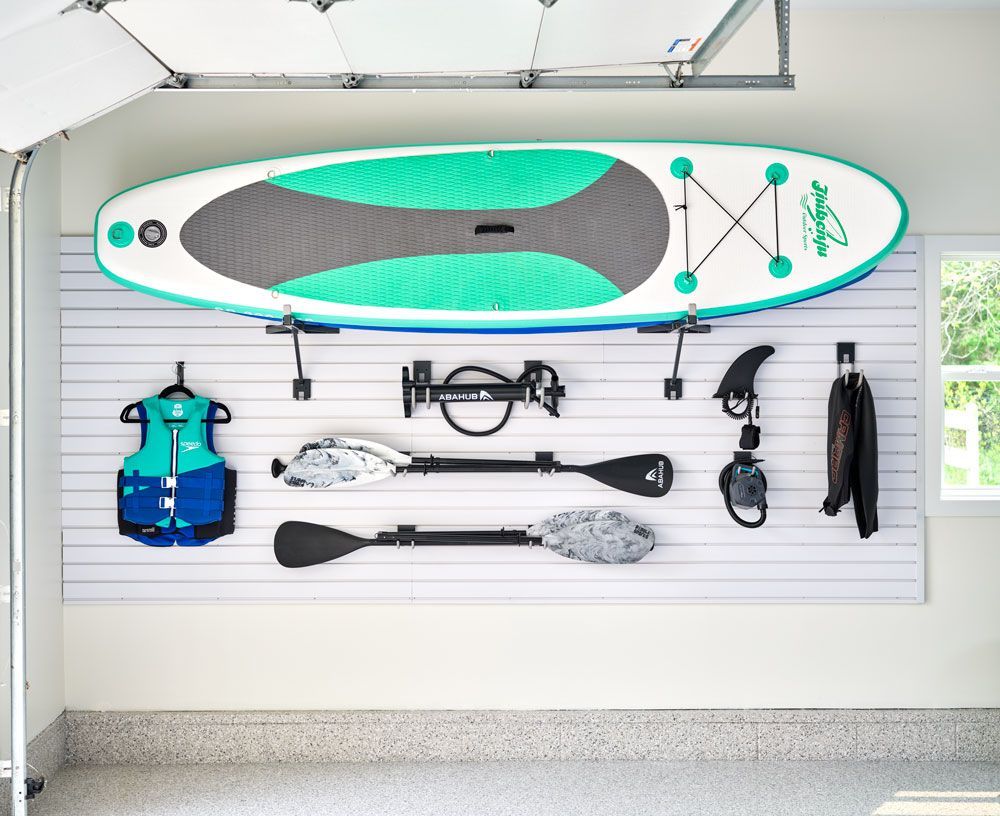 A paddle board is hanging on a wall in a garage.