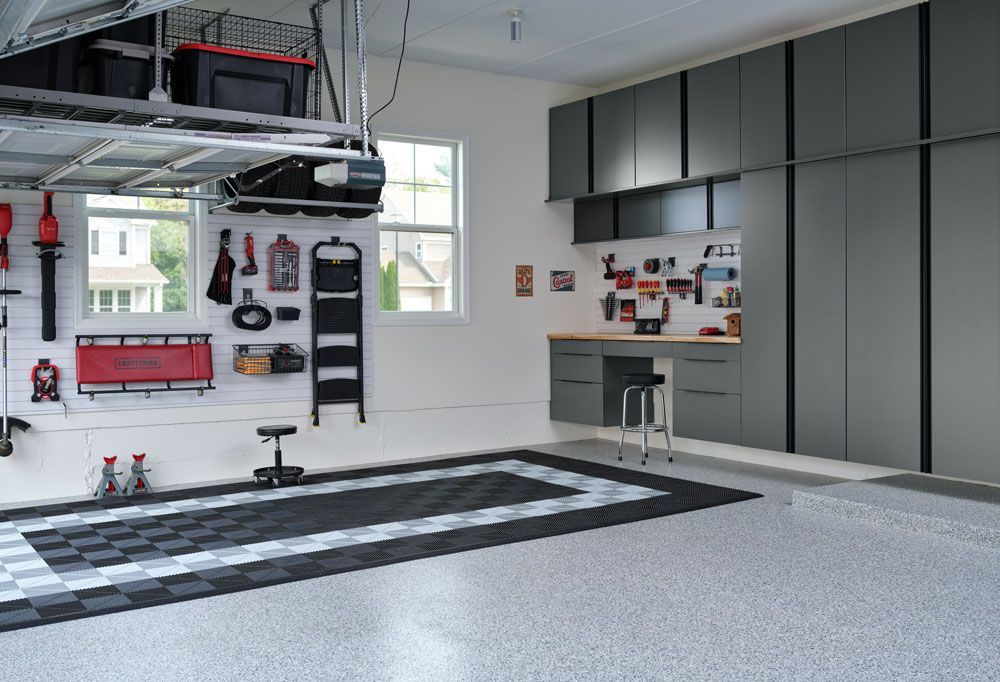 A garage with a black and white checkered floor and gray cabinets.