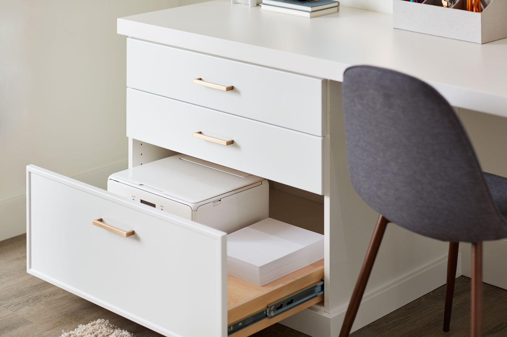 A white desk with a drawer open and papers in it.