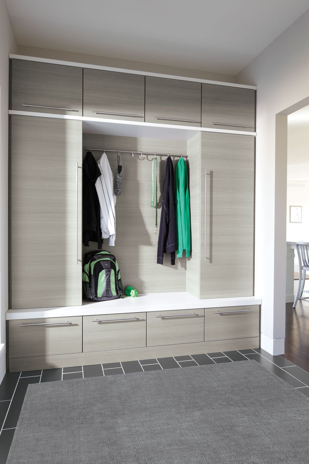 A hallway with a lot of cabinets and drawers and a rug.