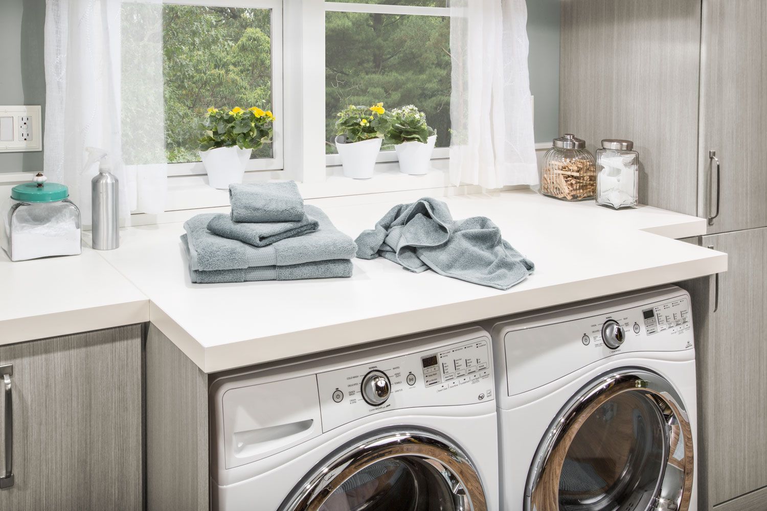 A laundry room with a washer and dryer and towels on the counter.