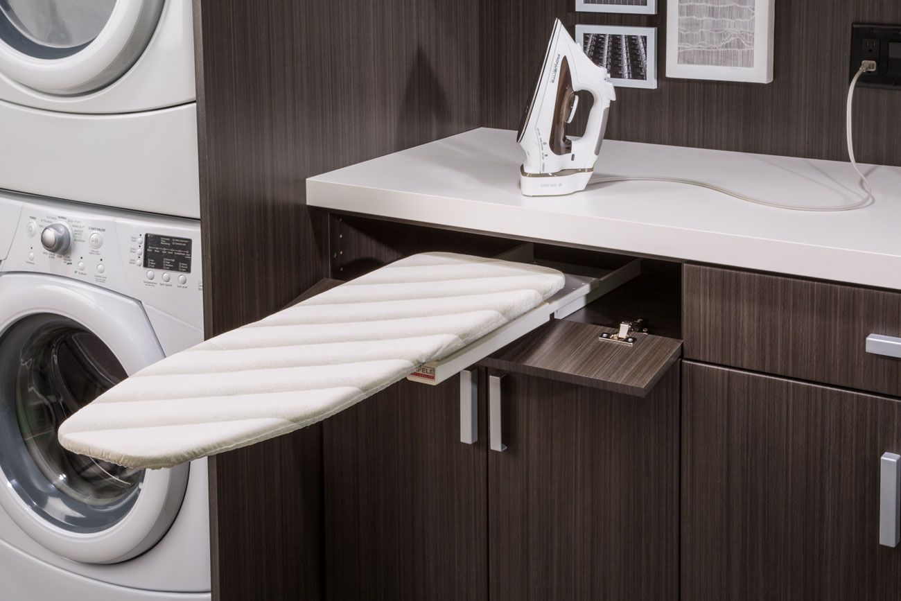 A laundry room with a washer and dryer and an ironing board
