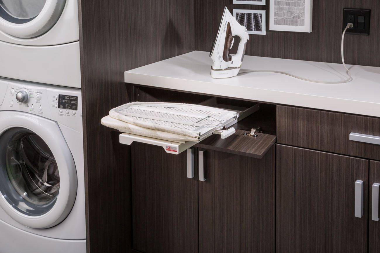 A laundry room with a washer and dryer and an ironing board