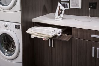 A laundry room with a washer and dryer and an ironing board