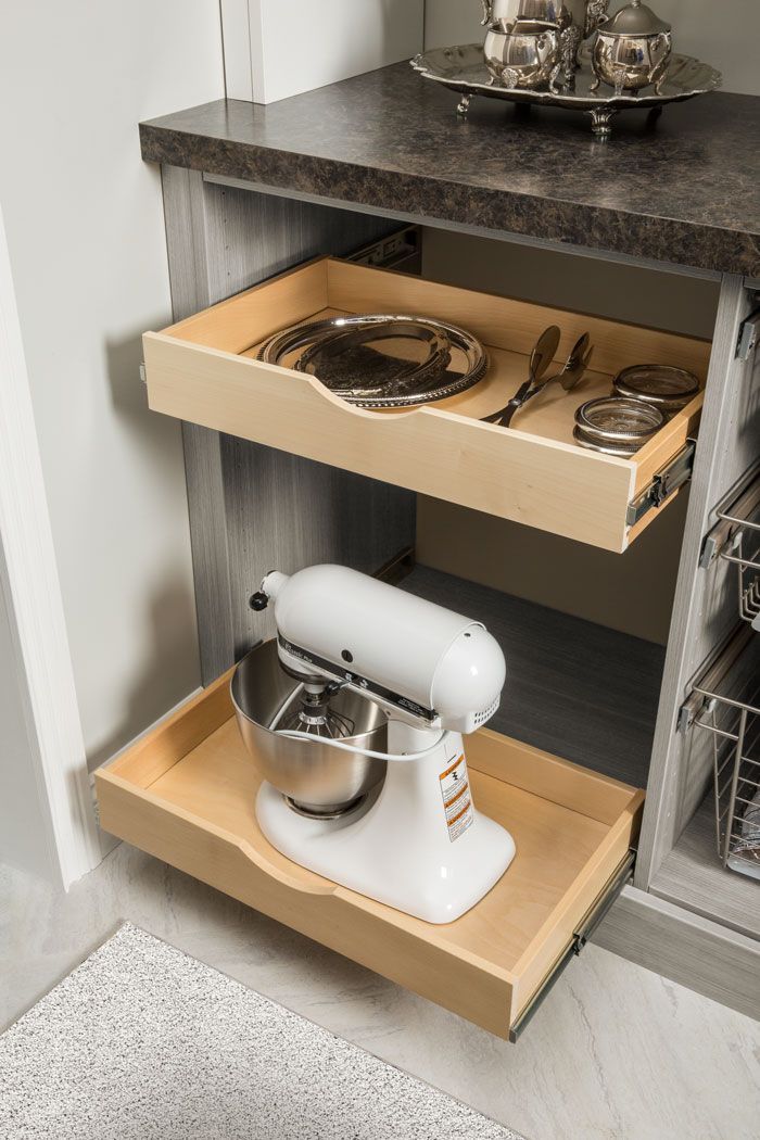 A mixer is sitting on top of a wooden drawer in a kitchen.