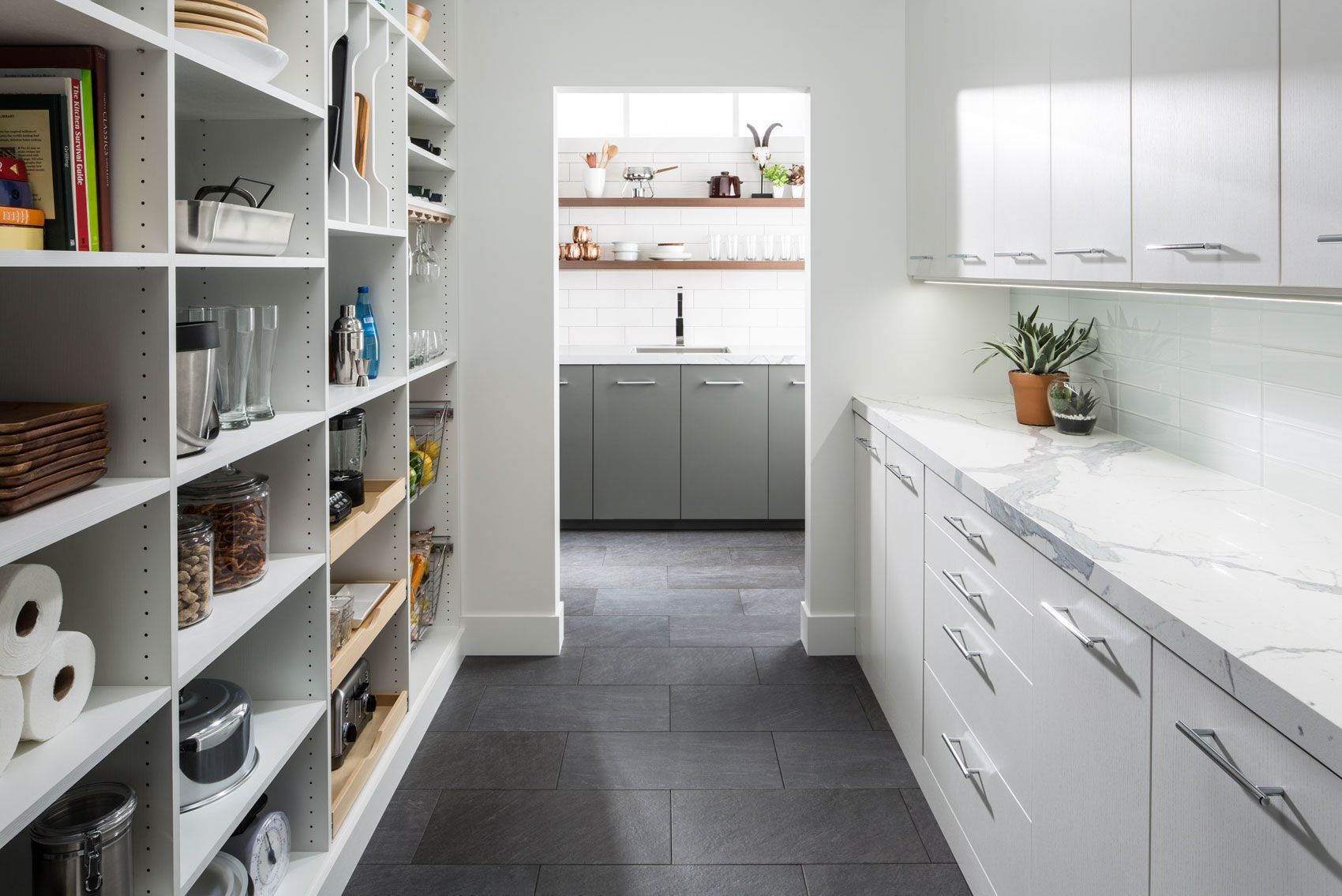 A kitchen with white cabinets and a pantry with lots of shelves and drawers.