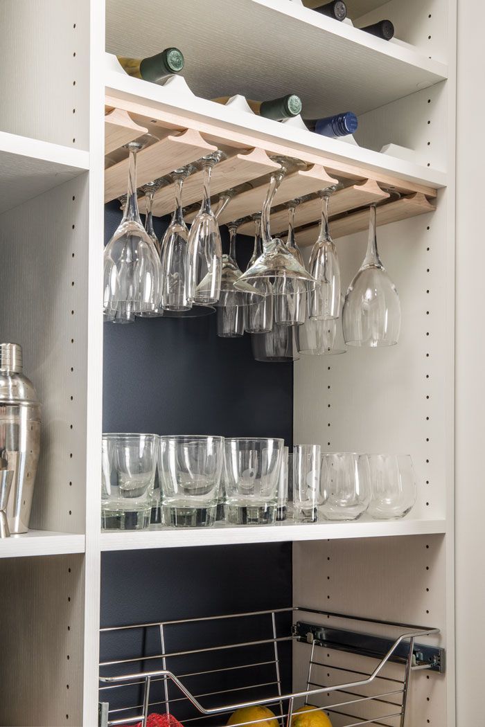 A wine rack with glasses hanging from it in a pantry.