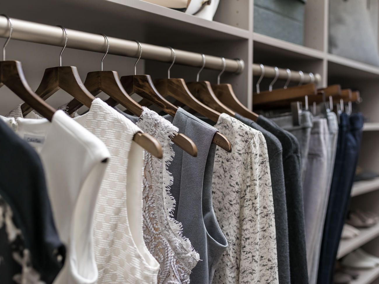 A closet filled with clothes hanging on wooden hangers.