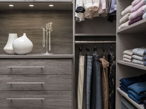 A closet with a dresser and shelves filled with clothes.
