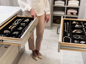 A woman is opening a drawer filled with jewelry.