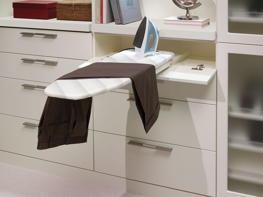A retractable ironing board in a laundry room with storage.
