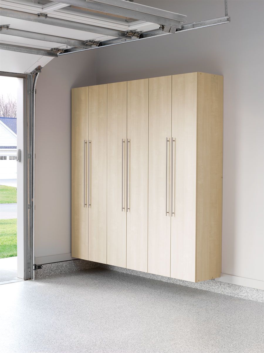 A garage with a lot of cabinets and a garage door open.