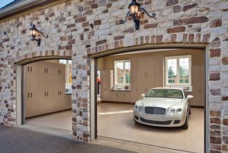 A white car is parked in a garage with the doors open.
