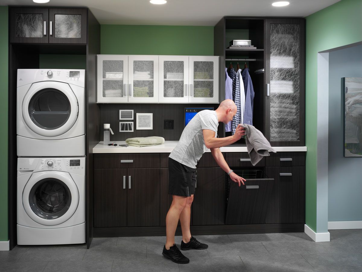 A man is standing in a laundry room with a washer and dryer.