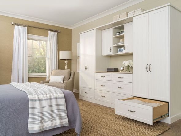 Custom reach-in closet with built-in cabinets and drawers in a bedroom.