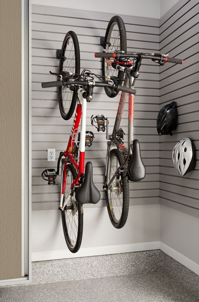 Two bicycles are hanging on a wall in a garage.
