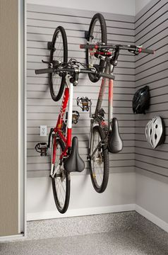 Two bicycles are hanging on a wall in a garage.