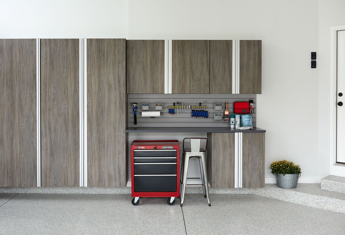 A garage with lots of cabinets and a red toolbox.