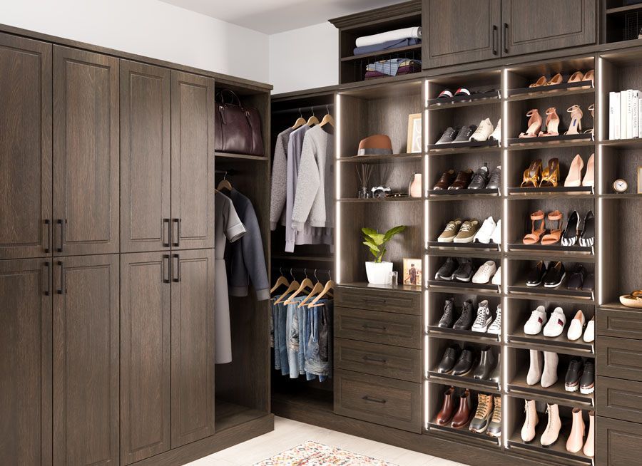 A walk in closet filled with lots of shoes and clothes.