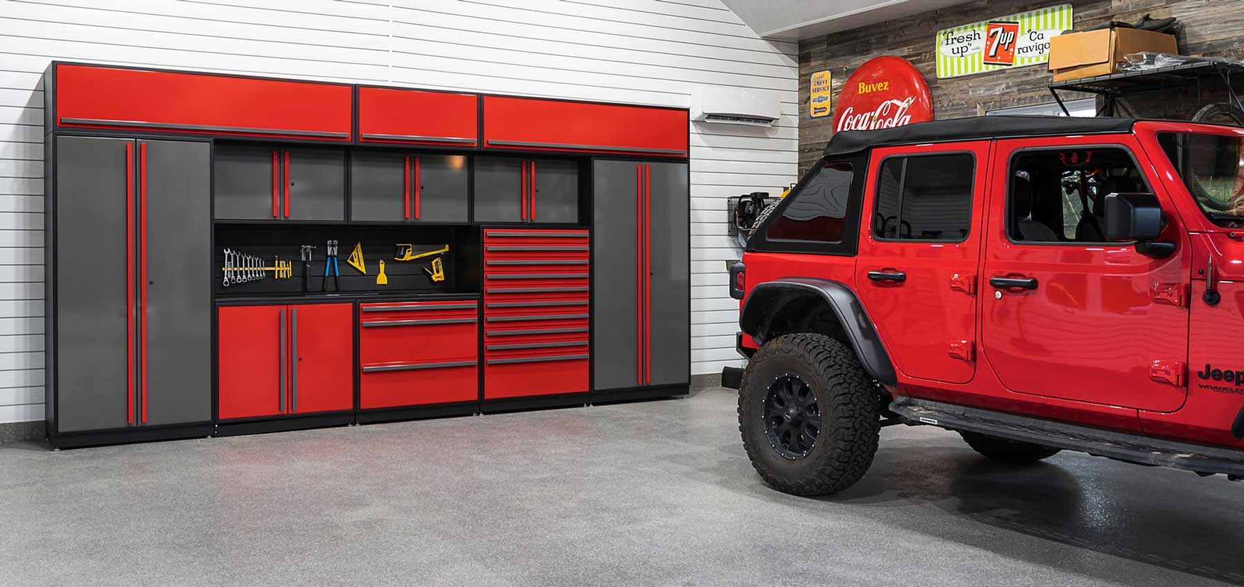 A car is parked in a garage with lots of cabinets and drawers.