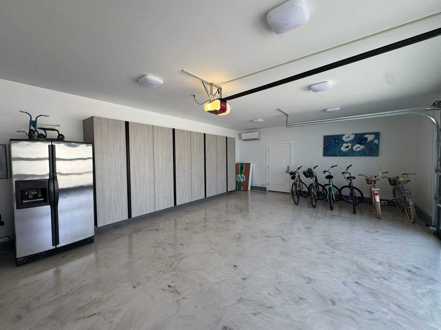 A car is parked in a garage with lots of cabinets.