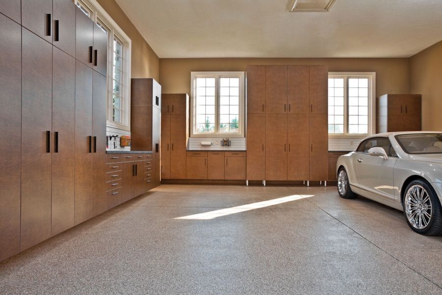 A car is parked in a garage with lots of cabinets.