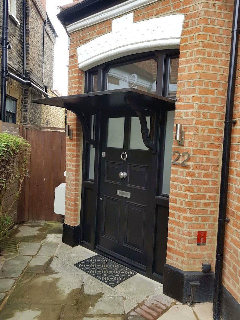 The front door of a brick building with a black door and a canopy over it.
