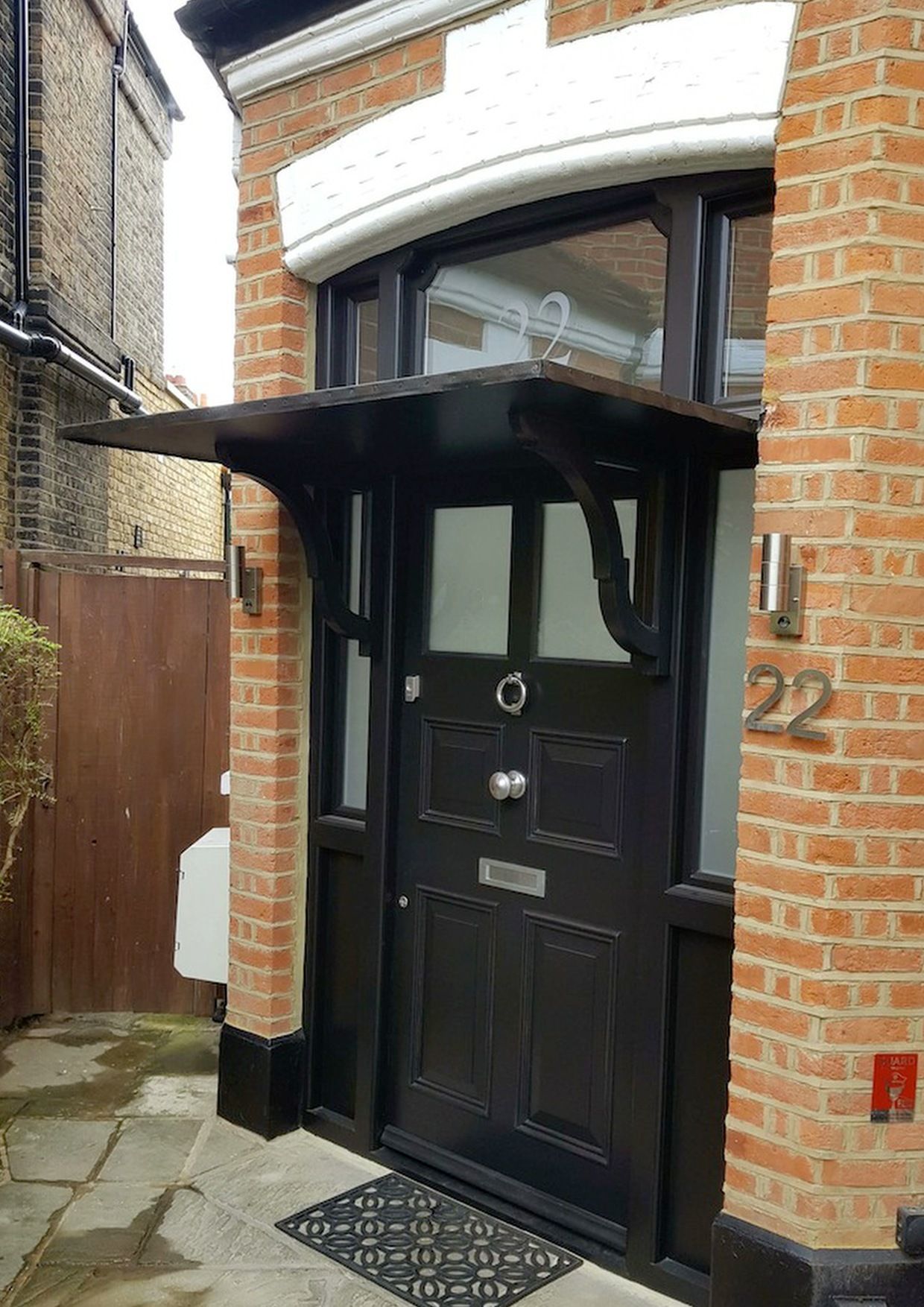 a brick home with an Accoya wood front entry door with the number 22 on it