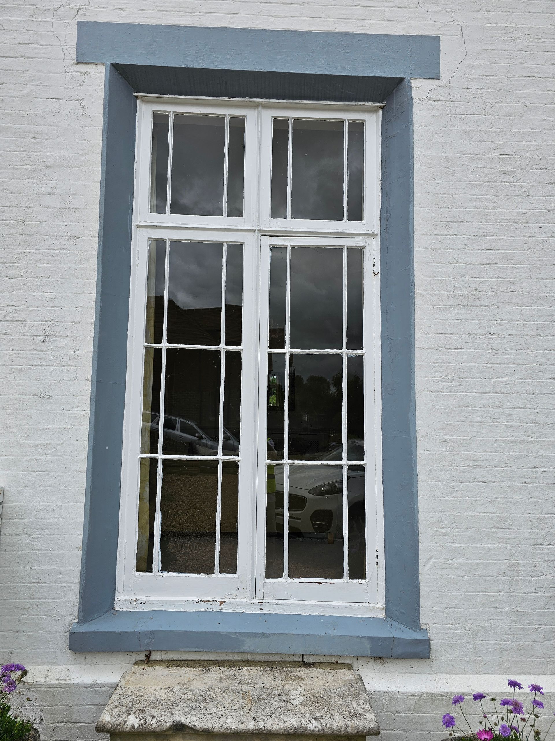 A white window with blue trim on a white brick building