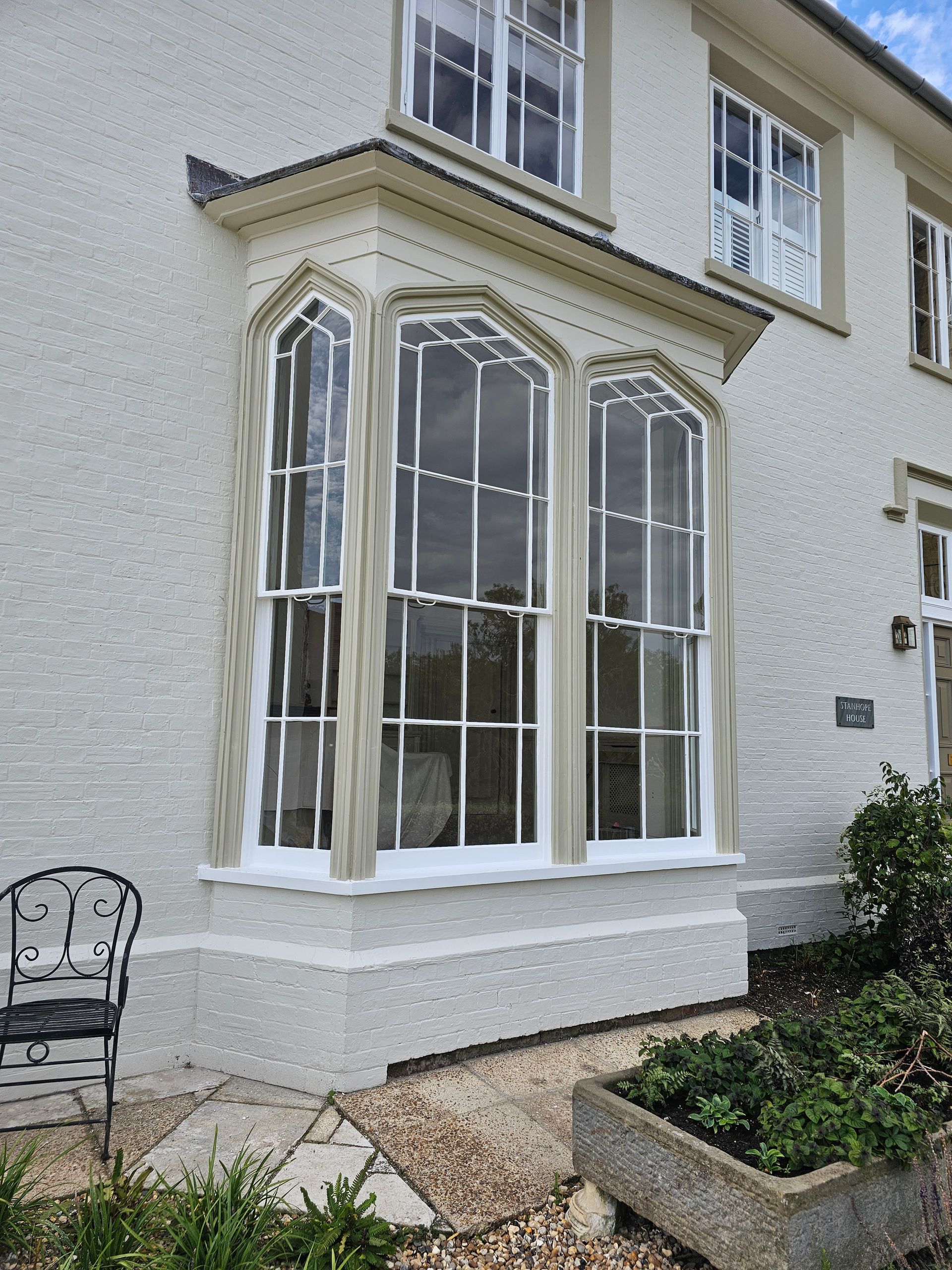 A white house with a large bay window and a chair in front of it.