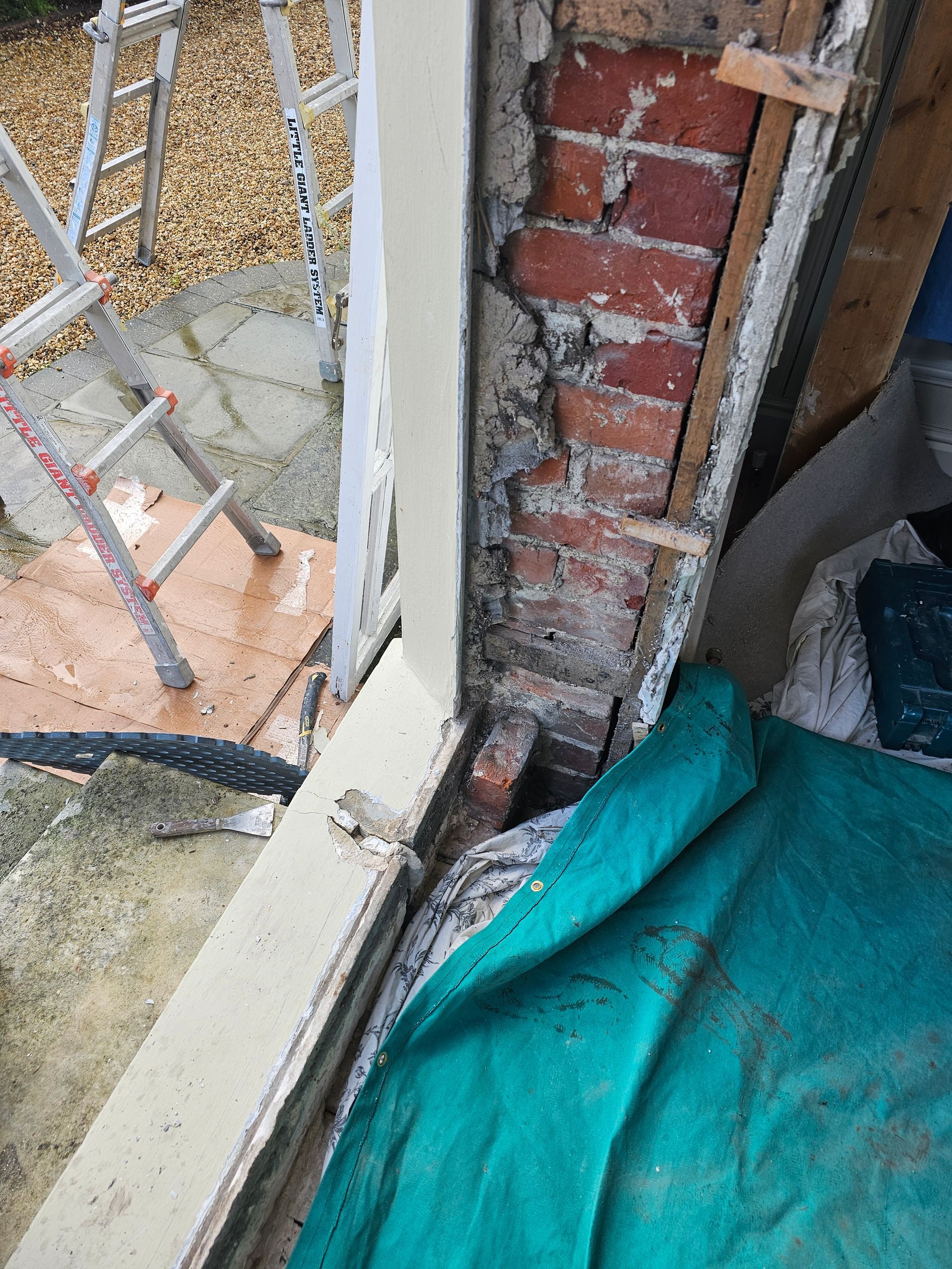 A ladder is sitting next to a window with a brick wall behind it.