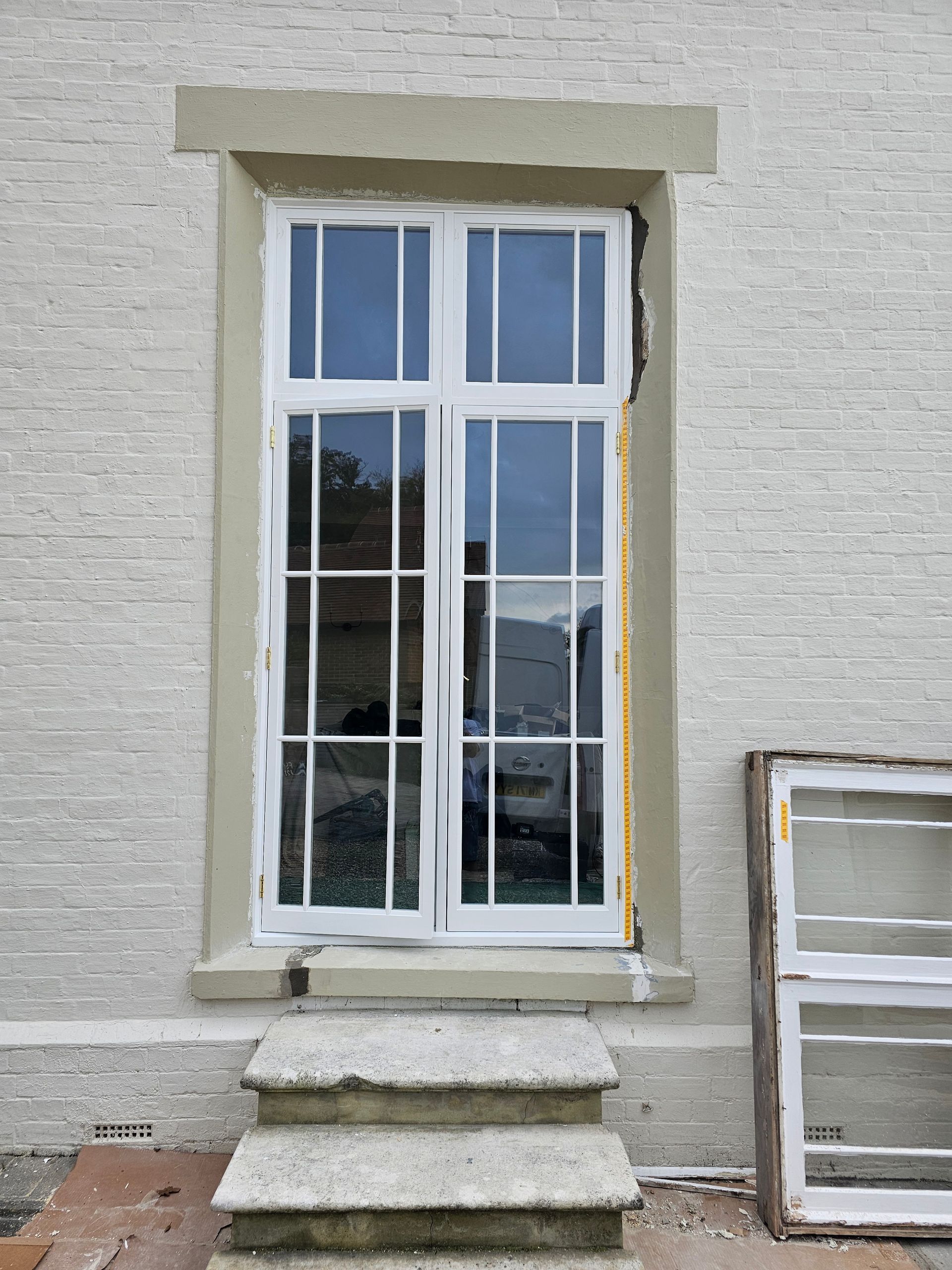 A white window on a white brick building with stairs leading up to it.