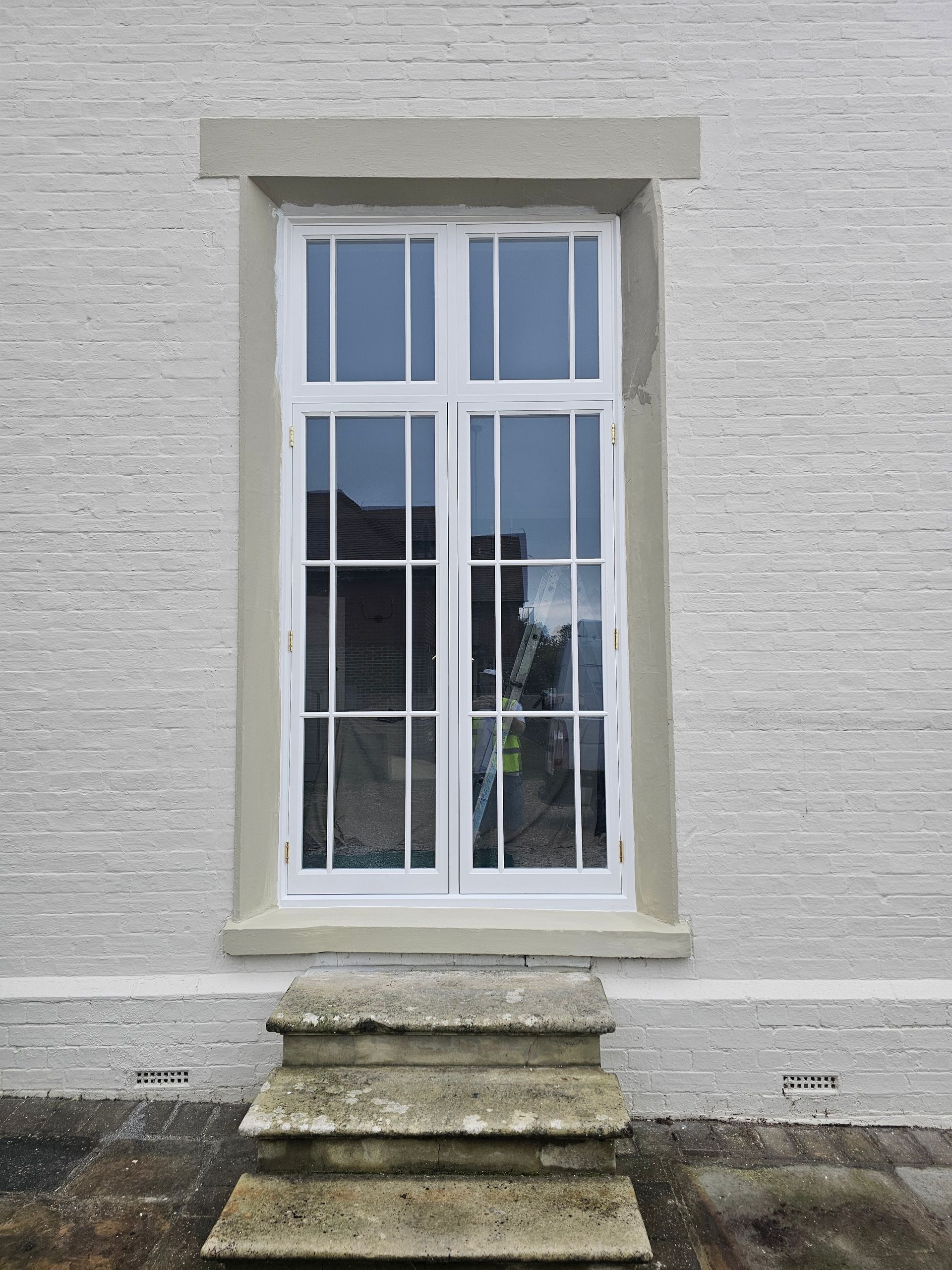 A white brick building with a window and stairs