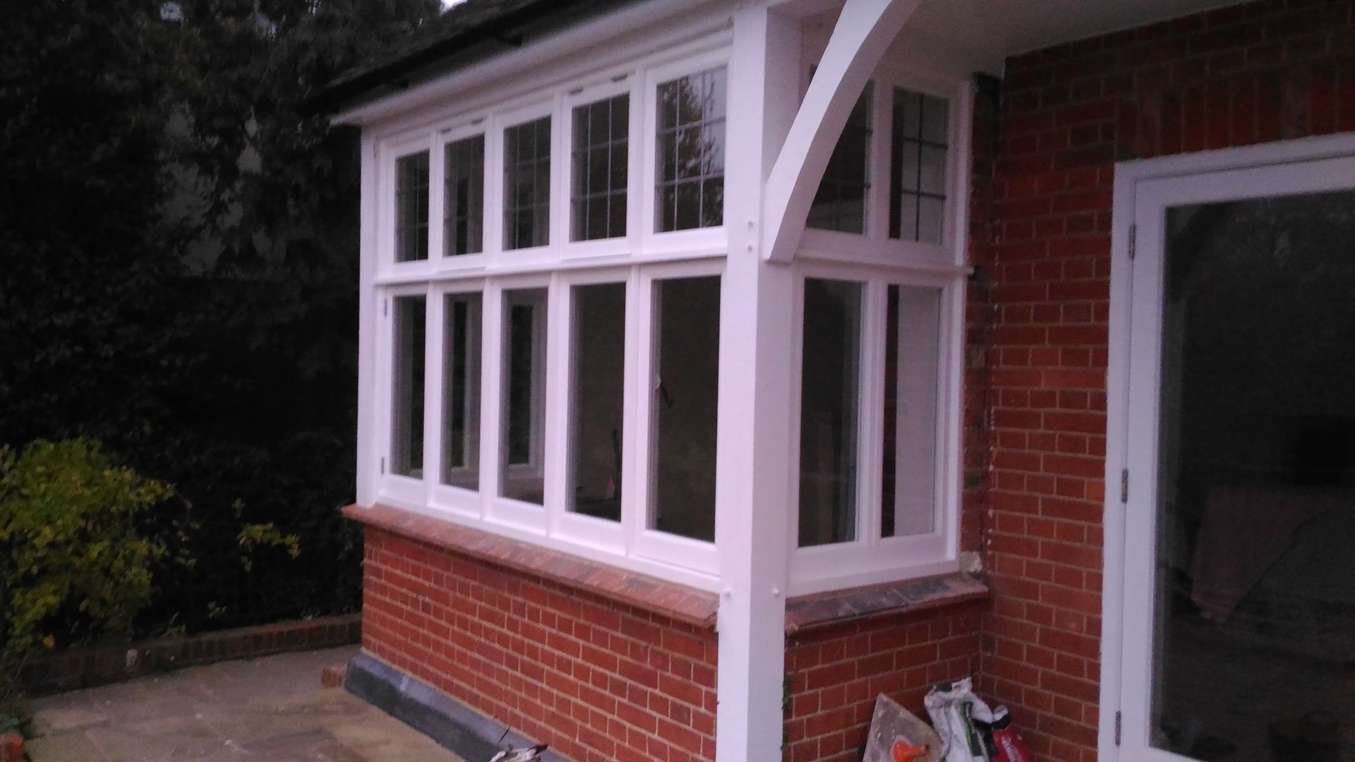 A brick house with a white porch and a white window.