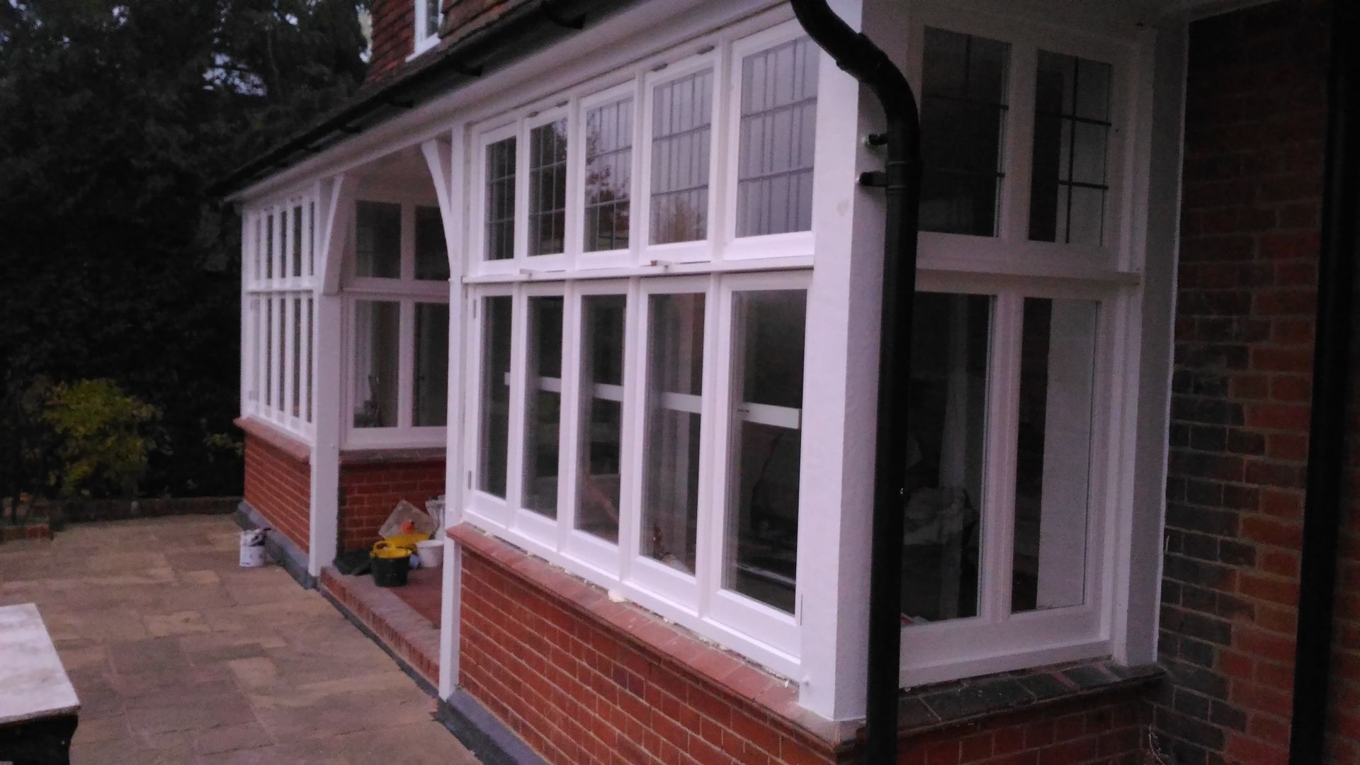 A white porch with a lot of windows on a brick house.
