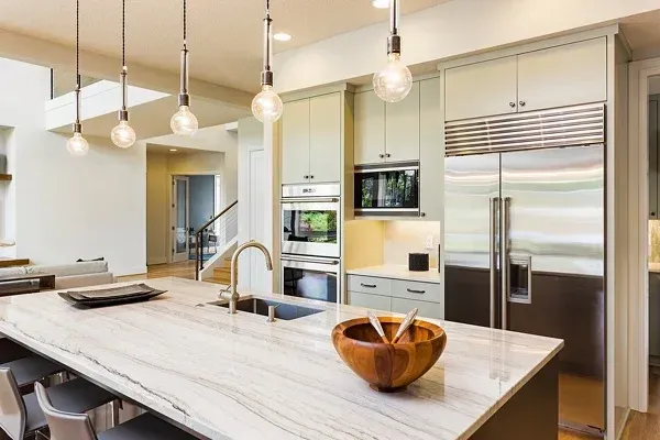 A kitchen with stainless steel appliances and a large island with a bowl on it.