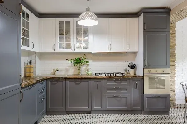 A kitchen with gray and white cabinets and a stove top oven.