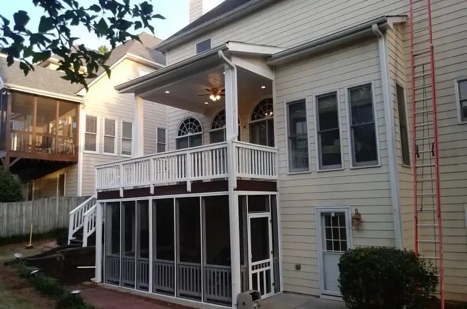 The back of a house with a screened in porch and stairs.