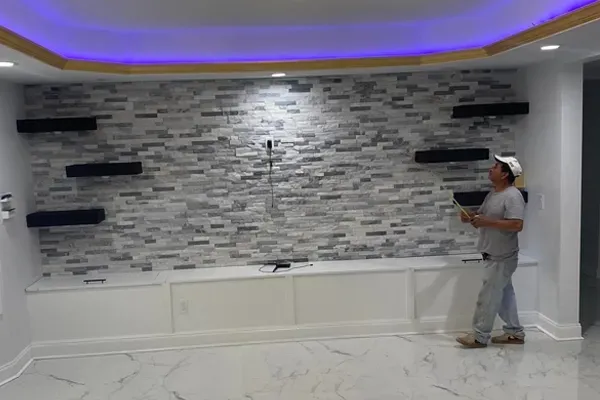 A man is standing in a room with a brick wall and shelves.