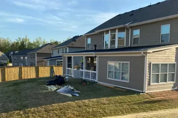 The backyard of a house with a screened in porch and a fence.
