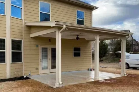 A large house with a covered patio and a white van parked in front of it.