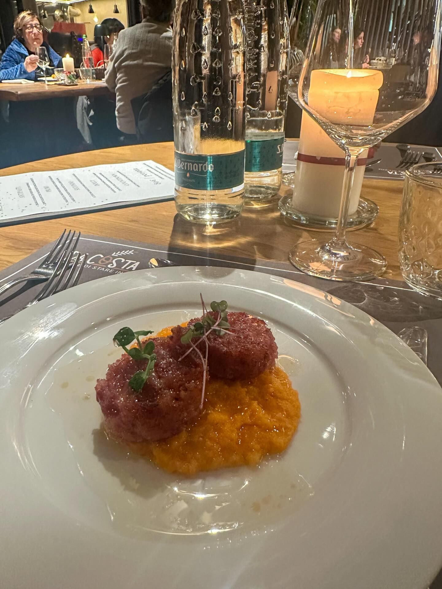 Piatto di cibo con due polpette di carne rotonde su purea di arancia, apparecchiato per la tavola da pranzo.