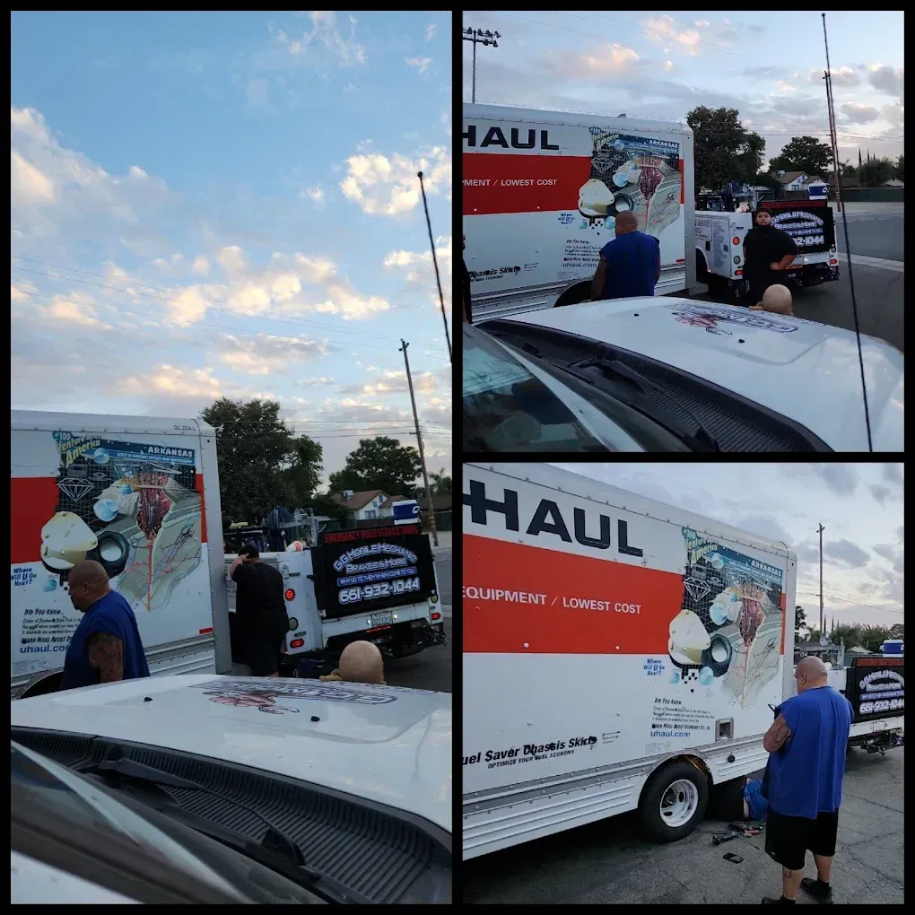 Three U-Haul trucks parked outside under a cloudy sky. People are present, some standing by the trucks.